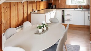 Een moderne keuken met witte kasten, een granieten aanrechtblad en een eethoek met een witte tafel en stoelen.