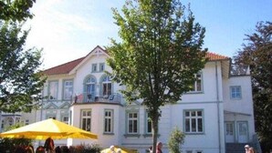 A building with a white facade, multiple windows, and a balcony. - (170) 1-room apartment - apartment house Sanssouci (Kühlungsborn)