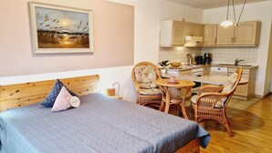 A bedroom with a bed, two chairs, a small table, and a painting on the wall. - (170) 1-room apartment - apartment house Sanssouci (Kühlungsborn)