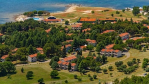 An aerial view of a coastal residential area with houses, a swimming pool, and a beach. - Bungalow with outdoor pool (Umag)