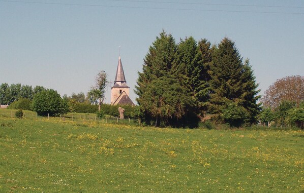 A rural landscape with a church and a large tree.