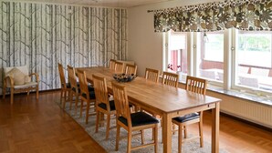 A dining room with a wooden table and chairs, a patterned wallpaper, and a window with a view. - Amazing home in Bolmsö with sauna (Bolmsö)