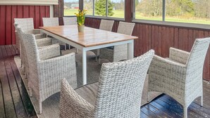 A covered outdoor dining area with wicker furniture and a wooden table. - Amazing home in Bolmsö with sauna (Bolmsö)
