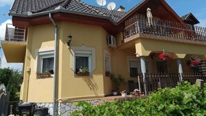 A two-story house with a balcony, satellite dishes, and potted plants. - Studio with garden and internet (Balatongyörök)