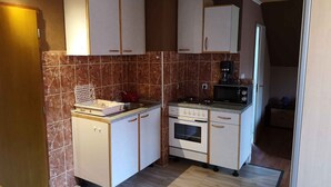 A compact kitchen with white cabinets, a microwave, a stove, and a coffee maker. - Studio with garden and internet (Balatongyörök)