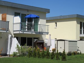 Un bâtiment à deux étages doté d’un balcon, d’un patio couvert et d’un petit espace extérieur aménagé pour s’asseoir.