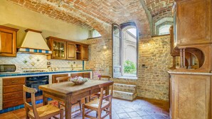 A rustic kitchen with exposed brick walls, wooden cabinets, and a stone floor. - Awesome apartment in Aramengo AT (Aramengo AT)