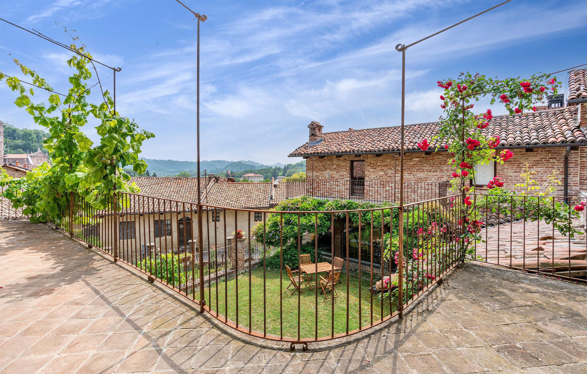 Un patio con un edificio de ladrillo, una cerca de metal y una mesa con sillas.