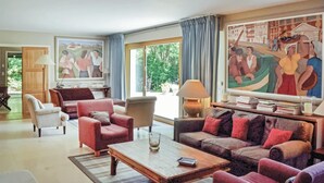 Uma sala de estar com um sofá, poltronas, uma mesa de centro e um quadro na parede.