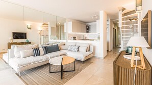 Ein modernes Wohnzimmer mit Sofa, Couchtisch und einer Küche im Hintergrund.