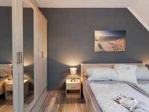 Ein Schlafzimmer mit Bett, Nachttischen, einer Lampe, einer Zeitschrift, einem Gemälde und einem Kleiderschrank.