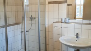 Une salle de bain avec une douche à parois de verre, un lavabo blanc et un miroir au-dessus du lavabo.