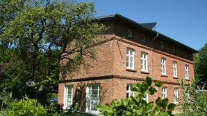 Un bâtiment en briques rouges, doté de nombreuses fenêtres et d’un toit en pente.