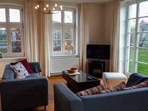 A living room with a sofa, a coffee table, a television, and a fireplace.