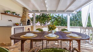 An outdoor dining area with a stone fireplace, a table set for four, and wicker chairs.
