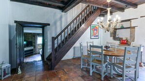 A rustic interior with a wooden staircase, a dining table with chairs, and a chandelier.