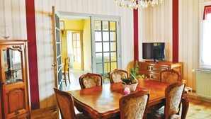 Ein Esszimmer mit Holztisch und -stühlen, einem Fernseher auf einer Kommode und einer Deckenleuchte.