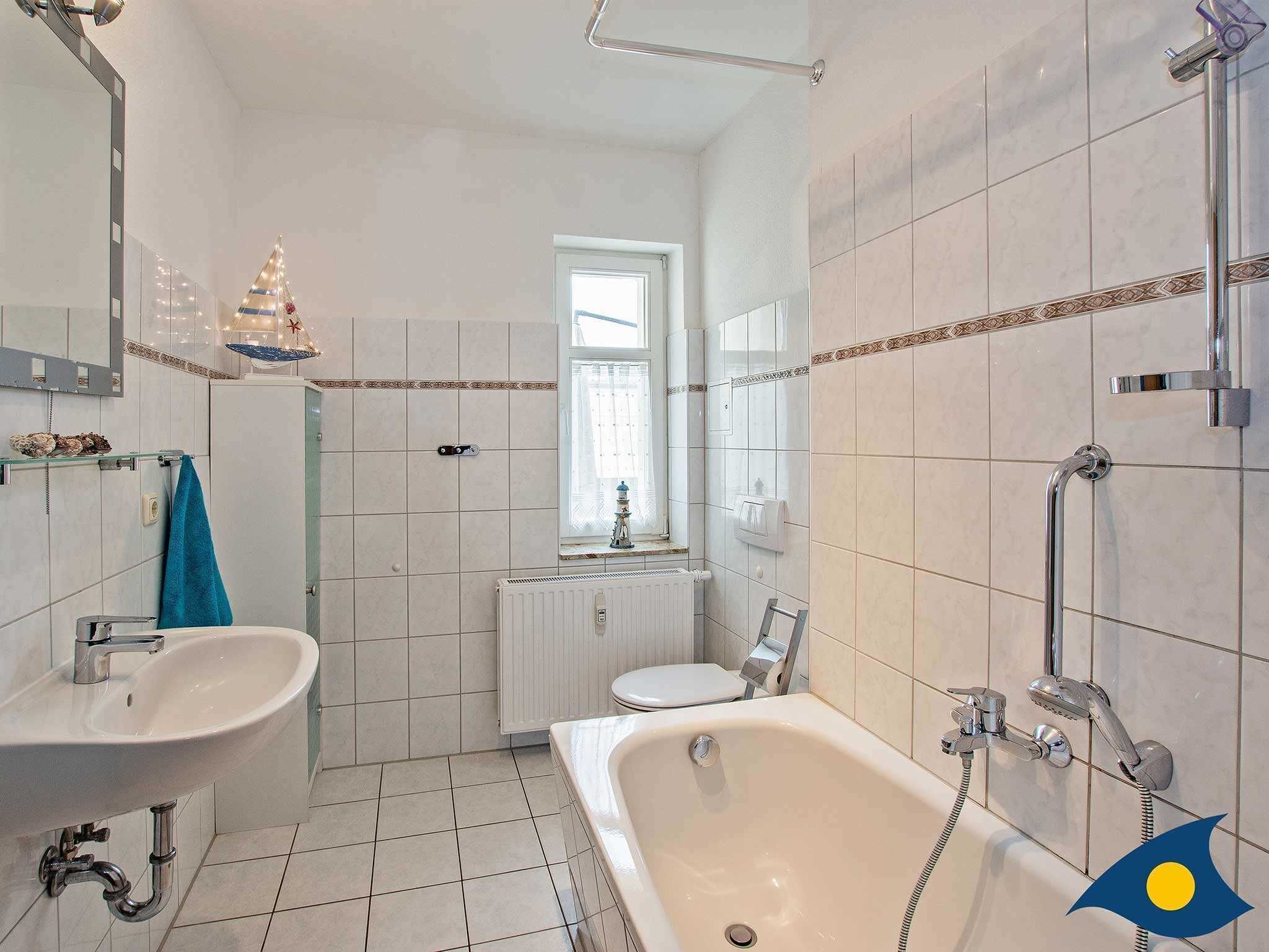 Ein Badezimmer mit einer Badewanne, einem Waschbecken, einer Toilette und einem Fenster.