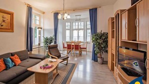 A modern living room with a sofa, coffee table, and a dining area in the background. - Villa Malve Whg. 05 - VMa 05 (Heringsdorf)