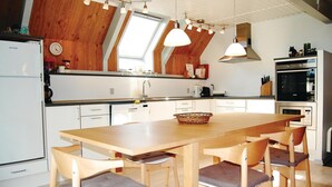 A modern kitchen with a large island, wooden chairs, and pendant lighting. - Lovely home in Humble with WiFi (Humble)