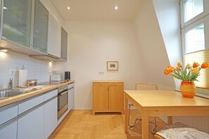 Une cuisine moderne avec une table en bois, un vase de tulipes et un tableau encadré accroché au mur.