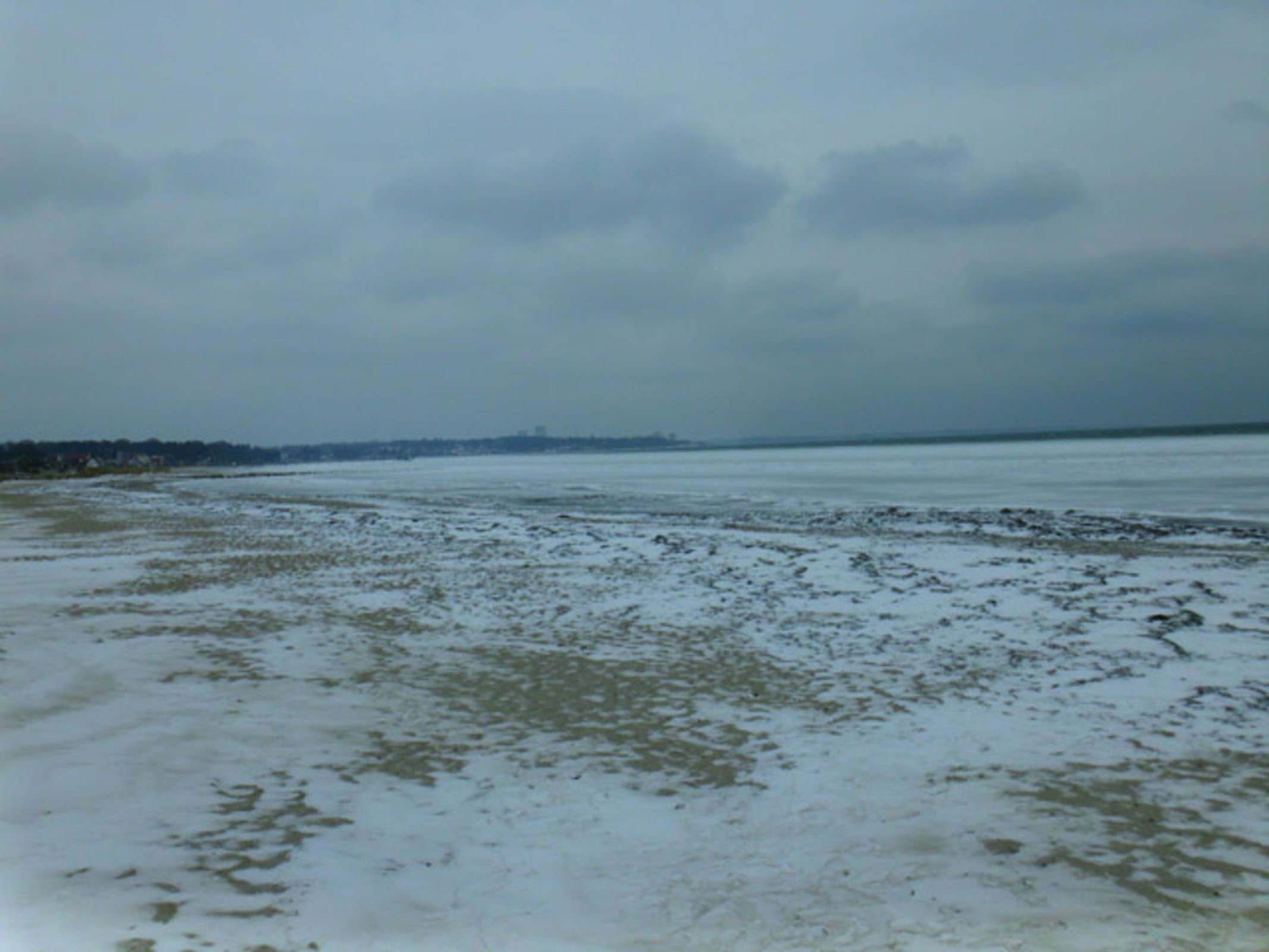A flat, open landscape with a distant horizon and a cloudy sky.
