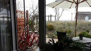A patio area with a table, chairs, a potted plant, and a bicycle. - Apartment Oystercatcher - beach house bay center (Scharbeutz)