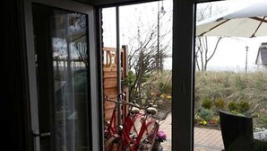 A room with a sliding glass door leading to an outdoor area with bicycles and a patio umbrella. - Apartment Oystercatcher - beach house bay center (Scharbeutz)