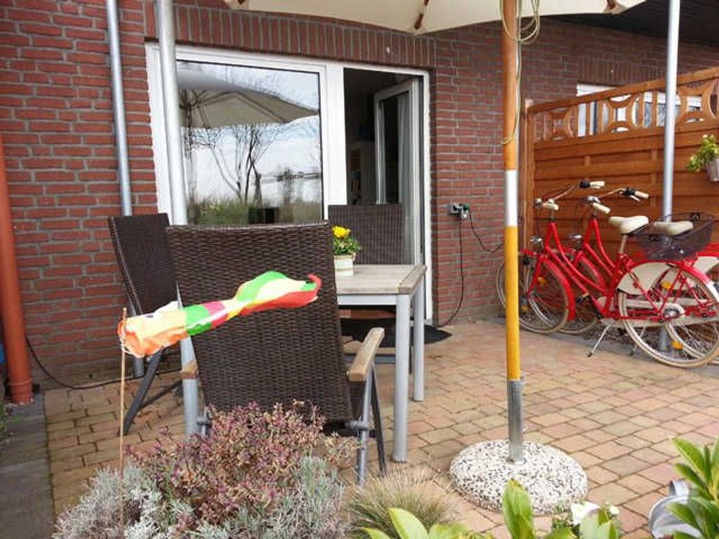 A patio with a wicker chair, a table, and a bicycle.