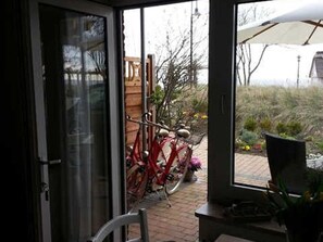 Habitación con puerta corrediza de vidrio que da a un espacio exterior con bicicletas y una sombrilla.