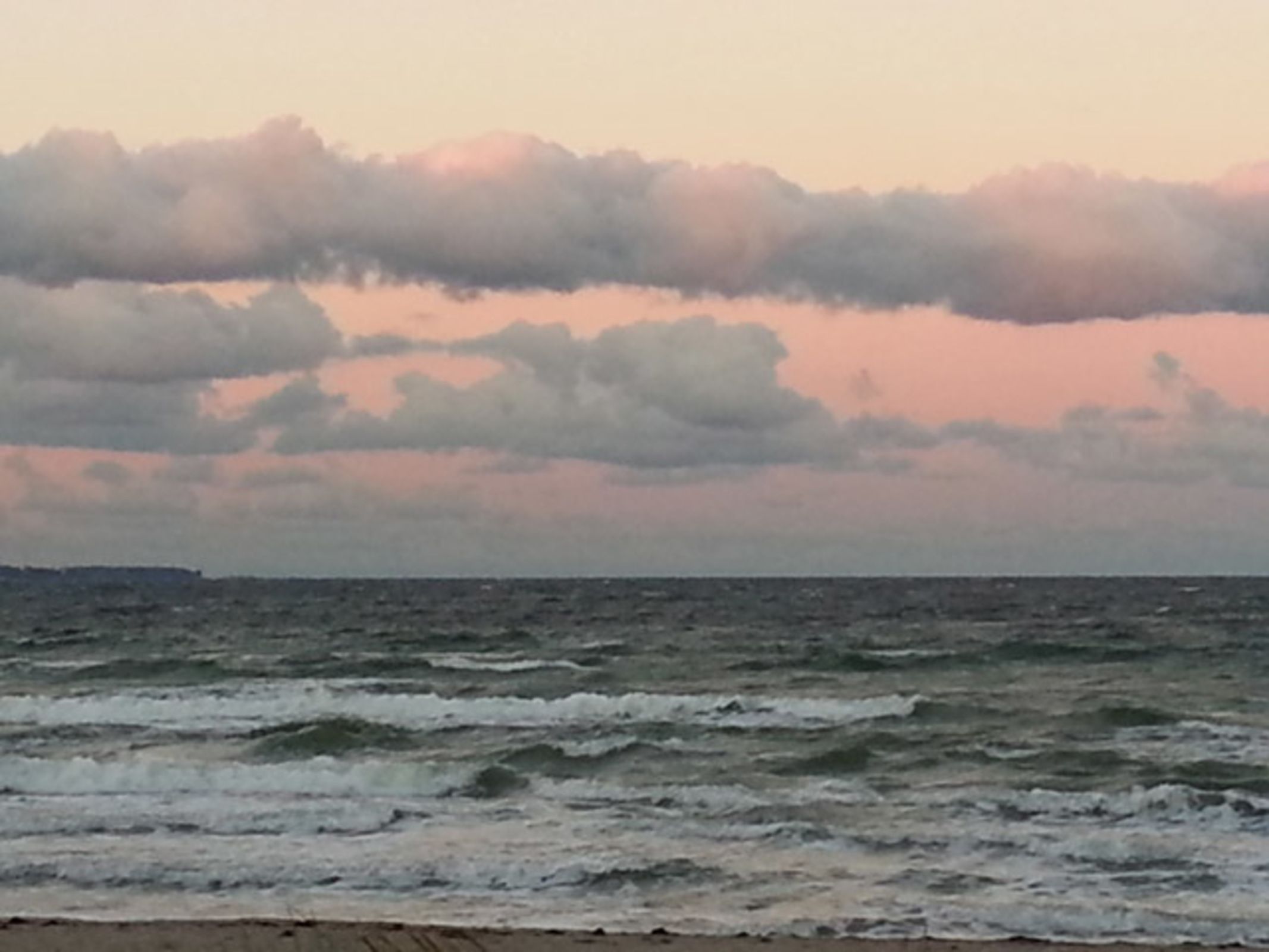 Una playa con olas y un cielo nublado.