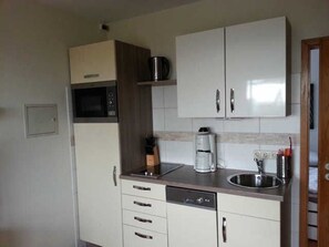 Una cocina compacta con microondas, cafetera y lavavajillas.