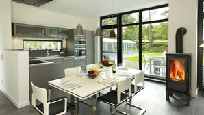 Una cocina moderna con comedor, ventanas amplias y estufa de leña.
