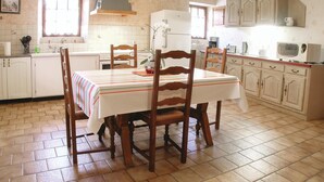 Una cucina con un tavolo da pranzo, sedie ed elettrodomestici essenziali.