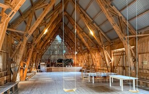 Un espaiós saló de fusta amb sostres alts i un altar central, amb bancs i taules per seure.