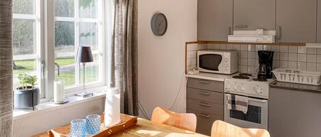 A kitchen with a window, a microwave, a stove, and a dining table with chairs.