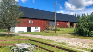 A red barn with a black roof, a gravel path, and a picnic table with chairs.