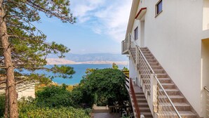 A building with a staircase leading to an outdoor area with a view of a body of water and mountains.
