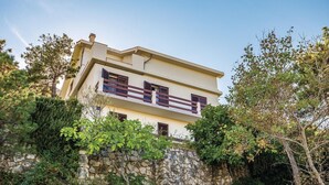 A two-story building with a stone retaining wall, multiple windows, and a balcony with a railing.