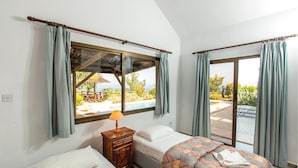 A bedroom with two beds, a nightstand, a lamp, and a view of a pool and outdoor area. - Stunning home in Argaka with WiFi (Argaka)