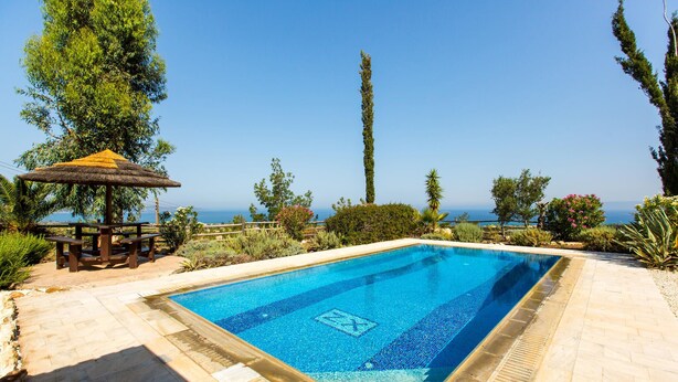 A rectangular swimming pool with a clear blue water surface, surrounded by a stone deck. - Stunning home in Argaka with WiFi (Argaka)