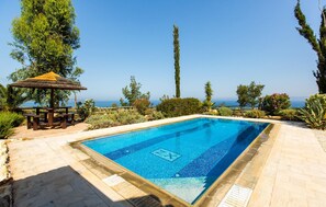 Una piscina rettangolare con superficie d'acqua azzurra e trasparente, circondata da un solarium in pietra.