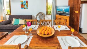 A dining area with a wooden table set for four, surrounded by wooden chairs. A large wooden bowl filled with oranges is placed in the center. - Stunning home in Argaka with WiFi (Argaka)