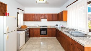 A kitchen with wooden cabinets, a built-in oven, a washing machine, and a microwave. - Stunning home in Argaka with WiFi (Argaka)