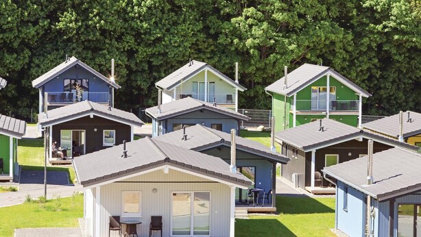 Une rangée de petites cabanes à un seul étage, dotées d’un toit plat, chacune comprenant un balcon et une porte-fenêtre coulissante.
