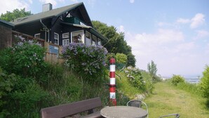 Een houten huis met een veranda, een bankje en twee stoelen buiten.