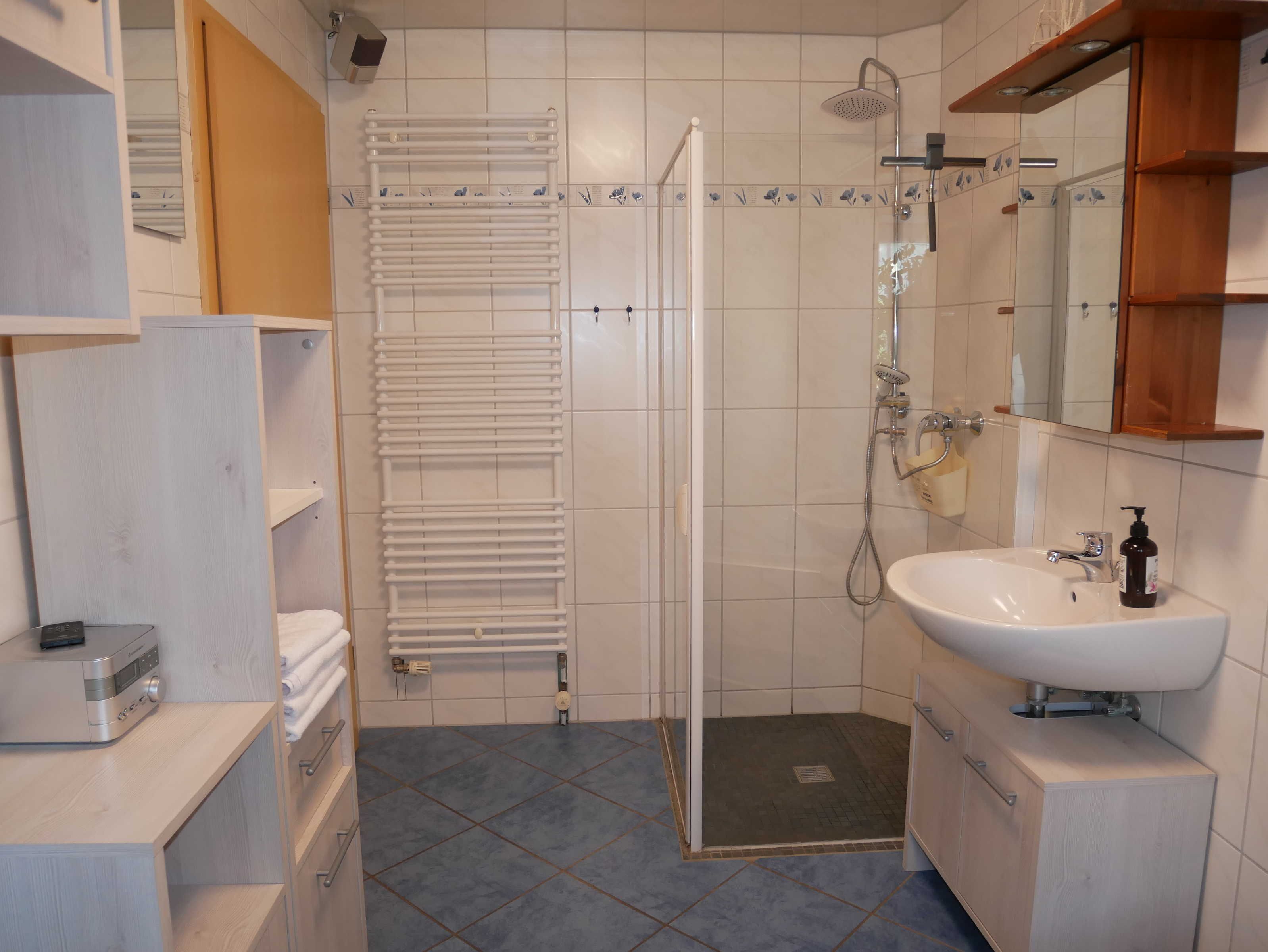A bathroom with a shower, sink, and towel rack.