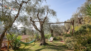 A garden with a hammock, a swing set, and various plants.