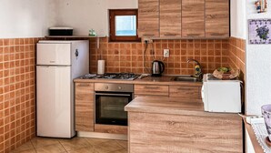 Uma cozinha compacta com geladeira, fogão, forno e pia.