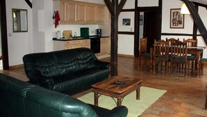 Un salon avec un canapé en cuir noir, une table basse en bois et un coin repas comprenant des chaises et une table en bois.